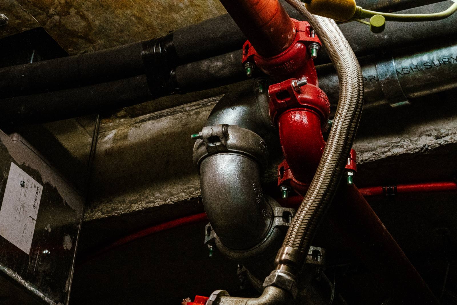 Grooved couplings and red sprinkler pipework in a ceiling void, Manly